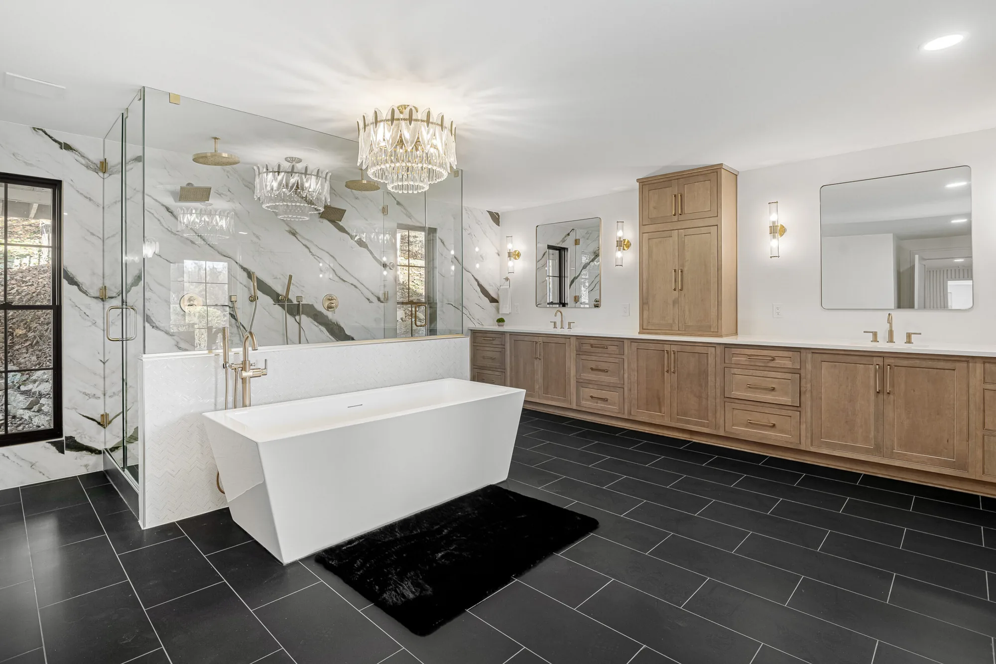 Remodeled primary bathroom with a freestanding tub, marble tile and a white oak vanity by Southern Belle Construction