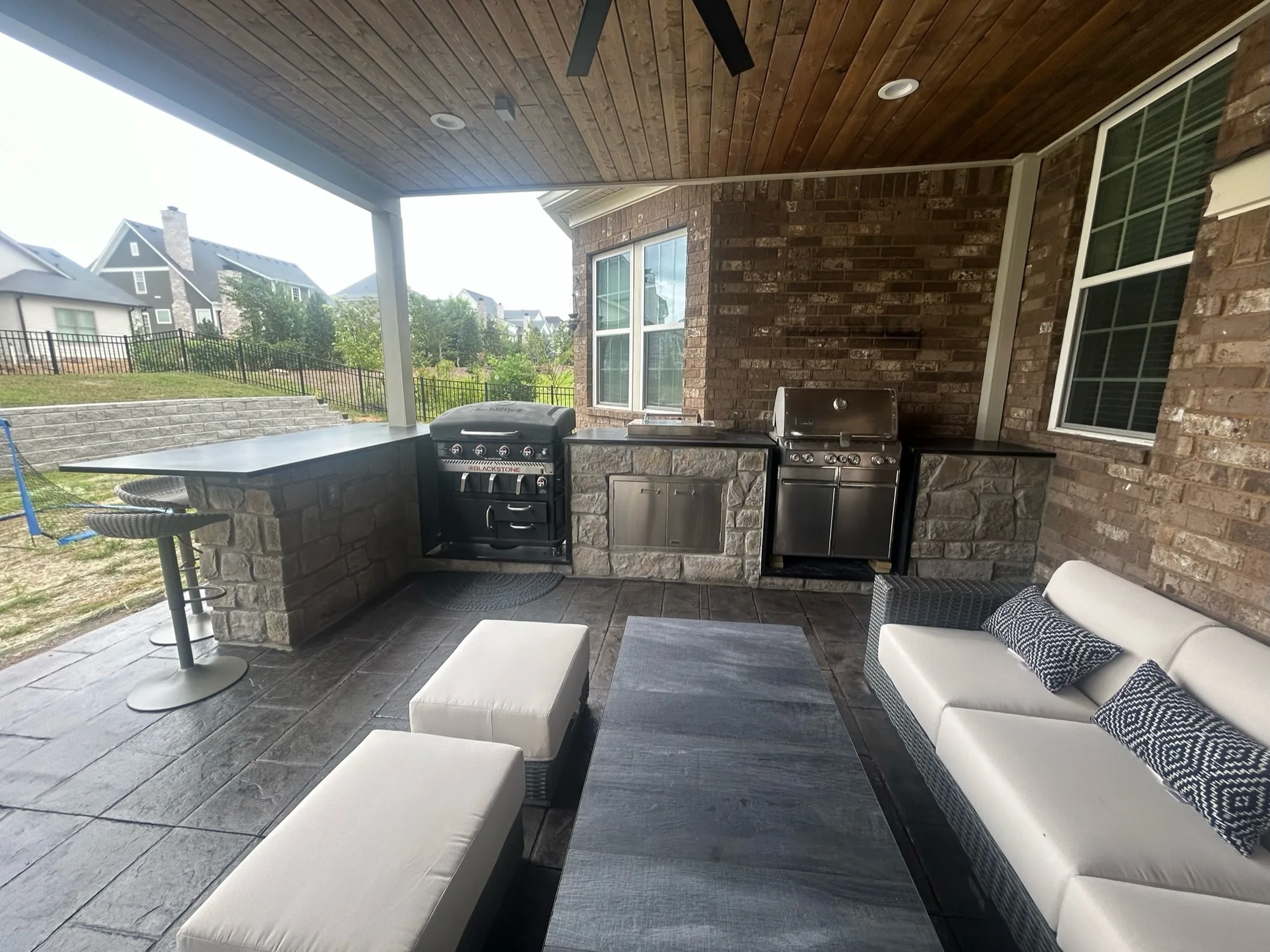 Covered patio with a stone outdoor kitchen, grill station and lounge seating built by Southern Belle Construction