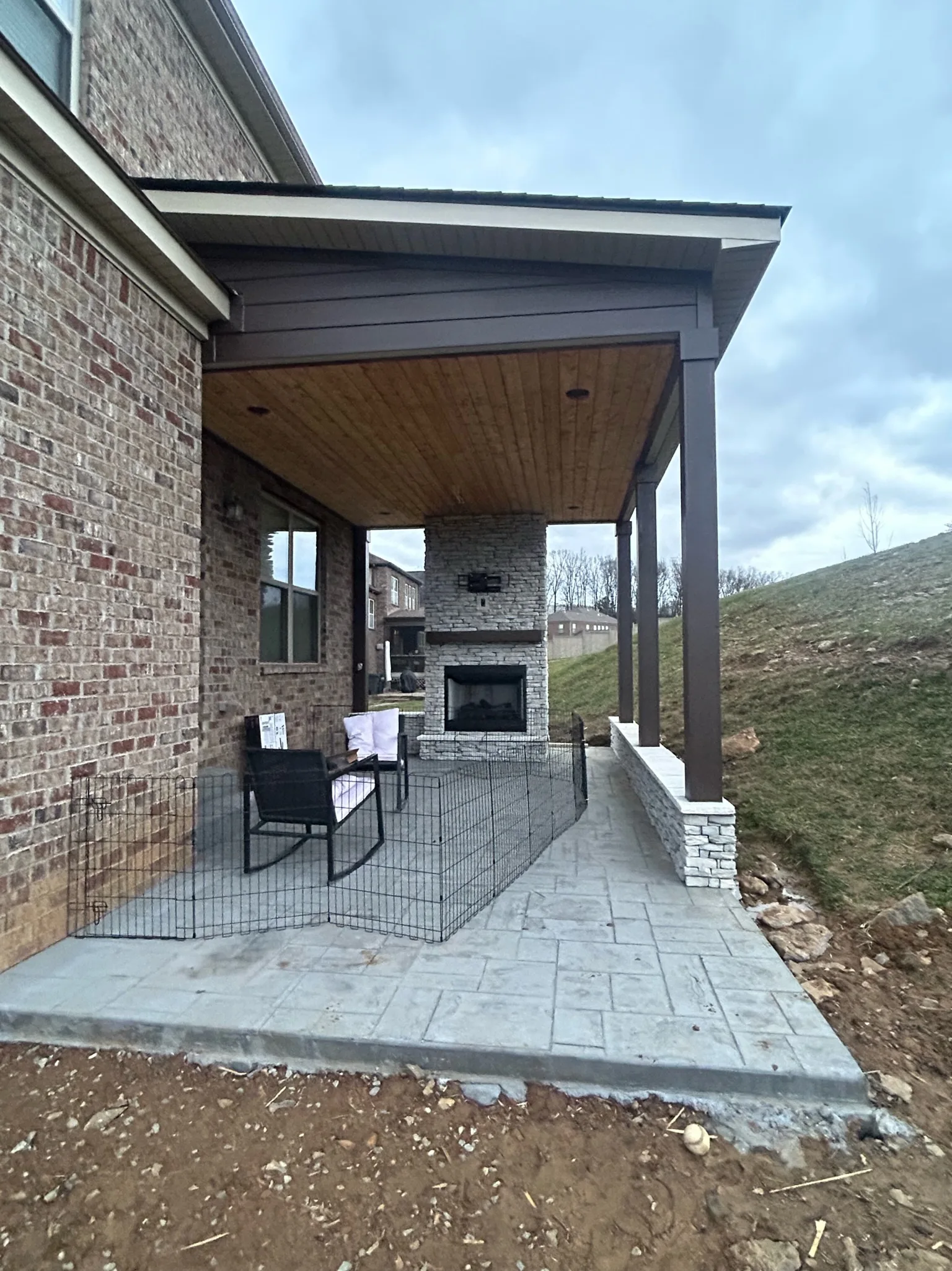 Brick home with a new covered back porch and outdoor fireplace, stained wood ceiling