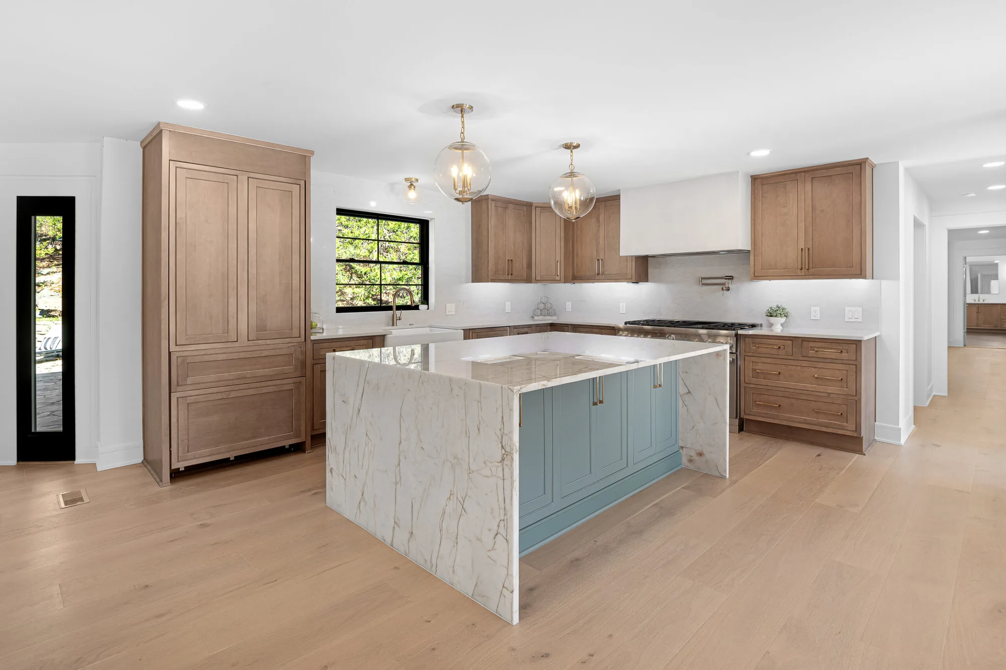 Remodeled kitchen with white oak cabinets and a marble waterfall island by Southern Belle Construction