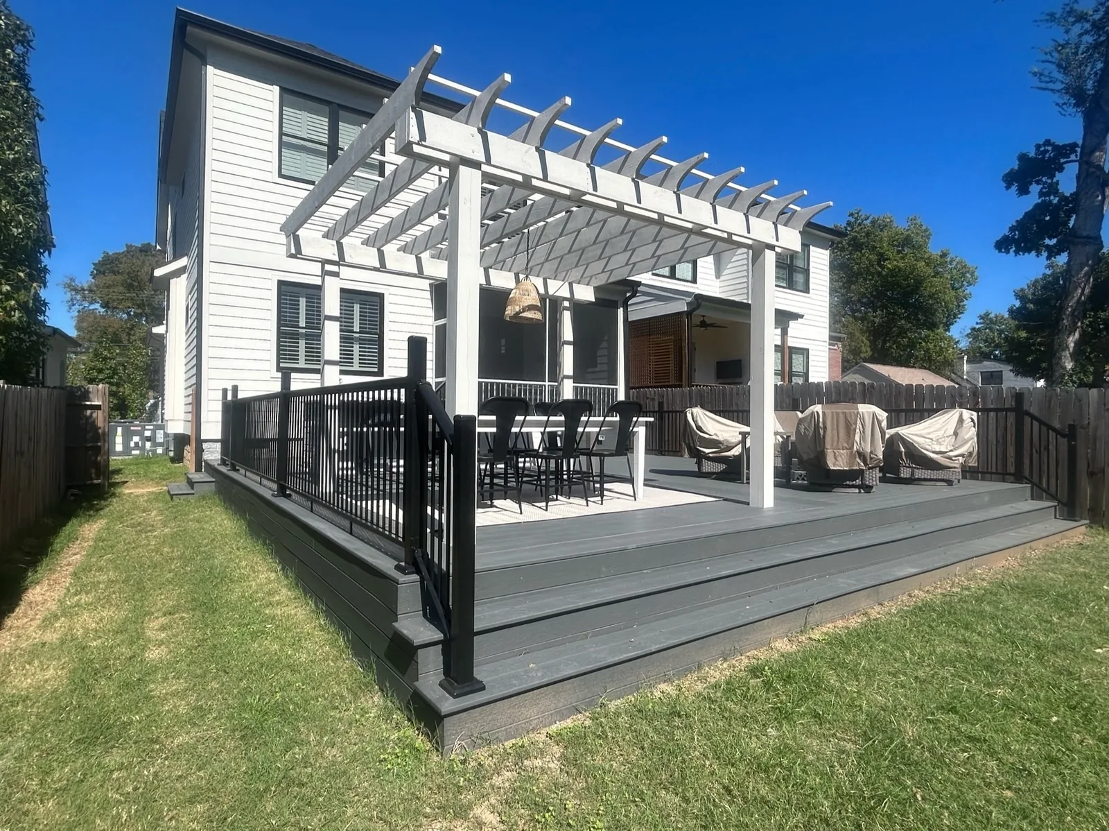 White pergola over a new composite deck on a two-story white farmhouse